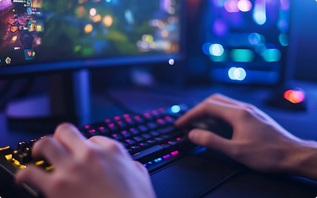 Egy játékos kezei a billentyűzeten és az egéren, miközben éjszaka RGB-megvilágítású számítógépen online játékot játszik.